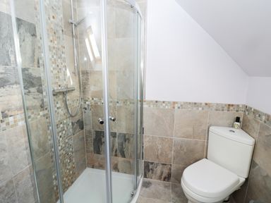 A bathroom with a corner shower enclosure and a toilet at Whinstones at 4 The Villas in Embleton