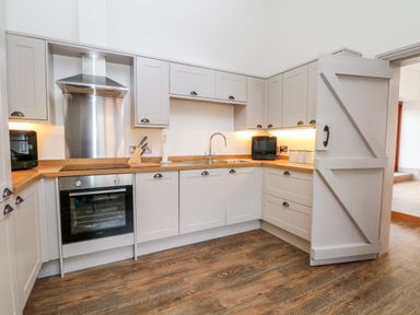 A kitchen with grey cabinets wooden countertops stainless steel oven and hood with a wooden floor at Lakeside Village Lodges & The Potting Shed in Capesthorne near Macclesfield