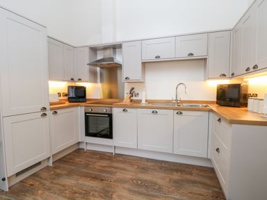 A kitchen with wooden countertops white cabinets a sink an oven and under cabinet lighting at Lakeside Village Lodges & The Potting Shed in Capesthorne near Macclesfield