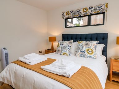 A bedroom with a bed linens bedside tables lamps and a window at Lakeside Village Lodges & The Potting Shed Capesthorne near Macclesfield