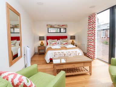 A bedroom with a bed bedside tables lamps and green chairs at Lakeside Village Lodges & The Potting Shed in Capesthorne near Macclesfield