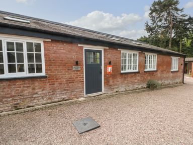 A brick building with white windows and a blue door labeled potting shed at Lakeside Village Lodges & The Potting Shed in Capesthorne near Macclesfield