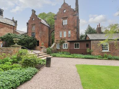 A gravel pathway with steps leading to brick buildings surrounded by plants and grass at Lakeside Village Lodges & The Potting Shed Capesthorne near Macclesfield