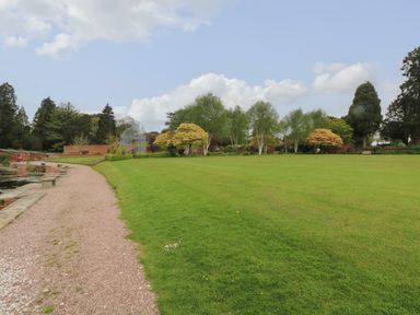 A garden with pathway trees and water feature at Lakeside Village Lodges The Potting Shed in Capesthorne near Macclesfield