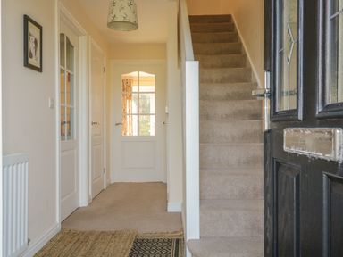 A hallway with a carpeted staircase and white doors at Rowan Cottage in St Bees