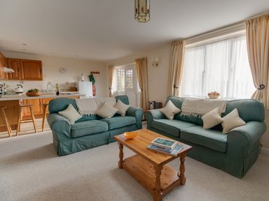 A living room with two green sofas a wooden coffee table and an open kitchen at Willow Barn in Cucklington near Wincanton