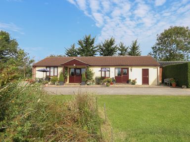 A single story house with brown roof and cream walls with garden and patio furniture outside at Willow Barn in Cucklington near Wincanton