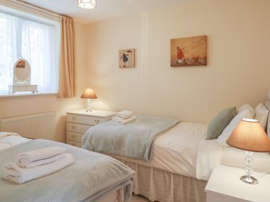 A bedroom with two single beds bedside tables lamps and wall art at Willow Barn in Cucklington near Wincanton