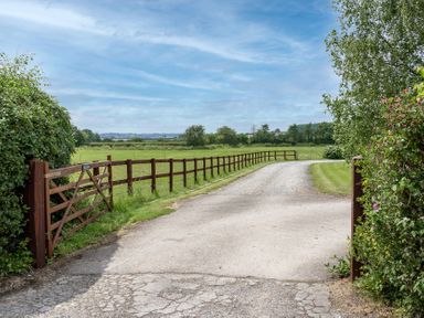 A gravel driveway leading through a gate and fence at Willow Barn Cucklington near Wincanton