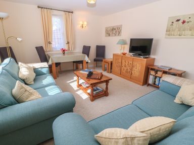 A living room with a sofa, TV, and a dining table at Willow Barn in Cucklington near Wincanton