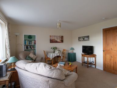 A living room with sofa armchairs coffee table TV and dining table at Little Barn Cucklington near Wincanton