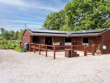 A stable with horse stalls and a water barrel at Little Barn in Cucklington near Wincanton