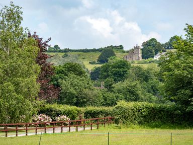 A view of trees and a church in the distance at Little Barn in Cucklington near Wincanton
