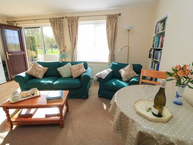 A living room with a sofa, table, and bookshelf at Little Barn in Cucklington near Wincanton
