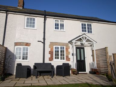 Front of a white two-story house with black door and outdoor black patio furniture at Willowbrook Cottage in Litton Cheney