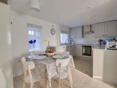 A kitchen with a dining table set for four and cabinets in Willowbrook Cottage in Litton Cheney