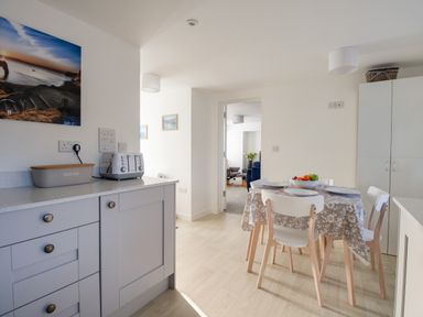 A kitchen with a table set for four and a countertop with a bread box and toaster at Willowbrook Cottage in Litton Cheney
