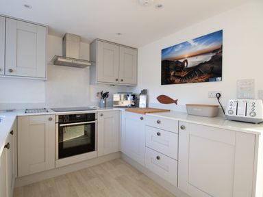 A kitchen with grey cabinets oven toaster bread box knives and a wall photo at Willowbrook Cottage in Litton Cheney