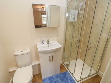 A bathroom with a toilet sink and shower enclosure with glass doors at Woodpecker Barn in Hensol near Pontyclun