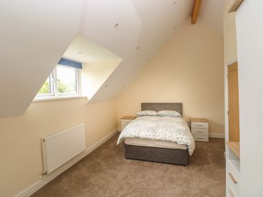 A bedroom with a double bed two bedside tables a window and a radiator at Woodpecker Barn in Hensol near Pontyclun