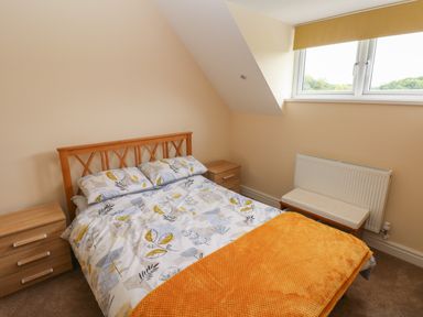 A bedroom with a double bed a wooden headboard two bedside tables and a window at Woodpecker Barn in Hensol near Pontyclun