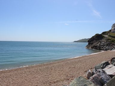 A pebble beach with rocks and a view of the sea and distant coastline at The Reach in Hallsands