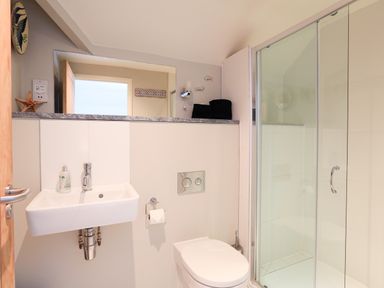 A bathroom with a sink toilet and glass shower enclosure at The Reach in Hallsands