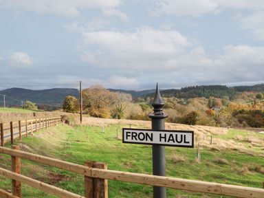 A rural landscape with a signpost that reads Fron Haul near a wooden fence Llanfwrog near Ruthin