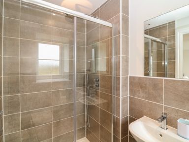A bathroom with a tiled shower enclosure and a sink with a mirror at Beacon House in St Agnes