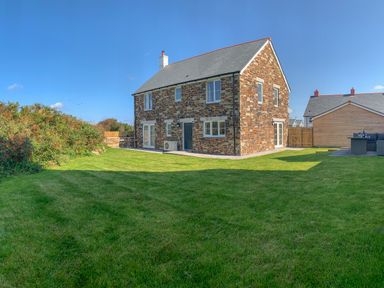 A stone house with a lawn and outdoor furniture at Beacon House in St Agnes