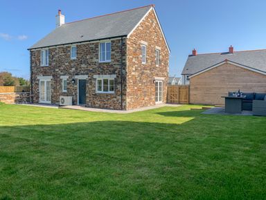 A stone house with a gray roof and a green lawn in front at Beacon House in St Agnes