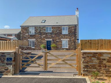 A stone house with a tiled roof behind a wooden gate at Beacon House in St Agnes