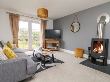 A living room with a gray sofa yellow pillows coffee table and fireplace at Beacon House in St Agnes