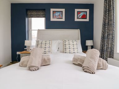 A bedroom with a bed with anchor pattern pillows and rolled towels on the bed at Beacon House in St Agnes