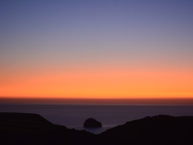 A coastal landscape with a rock formation in the sea at sunset with colorful sky at Glenhaven in Trewarmett near Tintagel