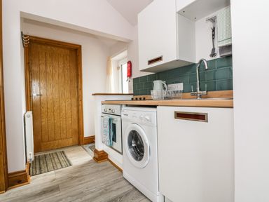 A kitchen with white appliances wooden countertops and a wooden door at Glenhaven in Trewarmett near Tintagel