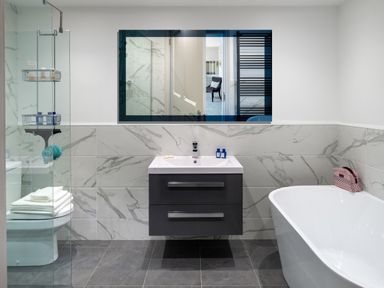 A bathroom with a sink and cabinet a bathtub a toilet with towels and a glass shower enclosure at Oakdene Country House in Sedbergh