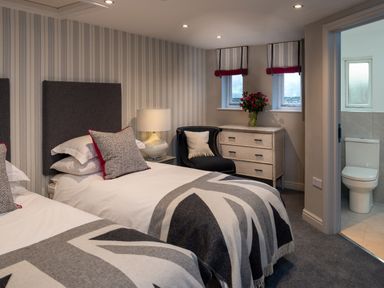 A bedroom with two single beds a chair a chest of drawers and an en suite bathroom at Oakdene Country House in Sedbergh