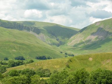 A valley with green hills and trees under a cloudy sky at Oakdene Country House in Sedbergh
