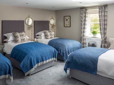 A bedroom with three single beds blue blankets and zebra patterned cushions at Oakdene Country House Sedbergh