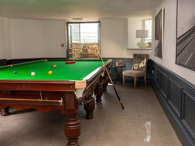 A snooker room with a green snooker table a chair and a table with drinks at Oakdene Country House in Sedbergh