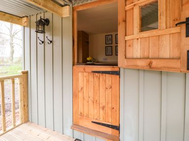 A wooden door with an open top half window and hooks on the wall on a small porch at Bracken Fern in Eppleby