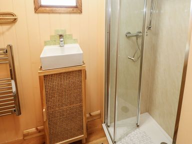 A bathroom with a sink on a wooden cabinet beside a glass-enclosed shower at Bracken Fern in Eppleby