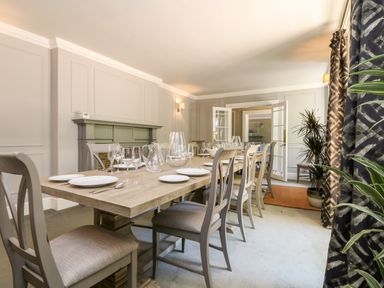 A dining room with a wooden table and chairs set with glassware and plates at Culdrose Manor in Helston
