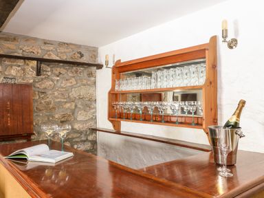 A bar area with wooden shelves holding glasses and a champagne bottle in an ice bucket at Culdrose Manor in Helston