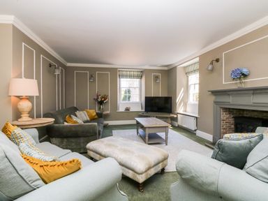A living room with sofas pillows a coffee table a television and a fireplace at Culdrose Manor in Helston