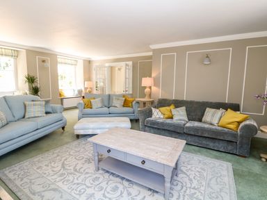 A living room with sofas cushions a coffee table and lamps at Culdrose Manor in Helston