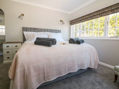 A bedroom with a large bed with rolled towels and a window with blinds at Culdrose Manor in Helston