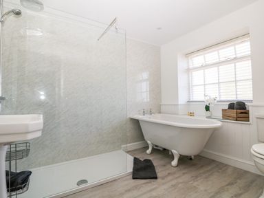 A bathroom with a walk in shower bathtub and window at Culdrose Manor in Helston