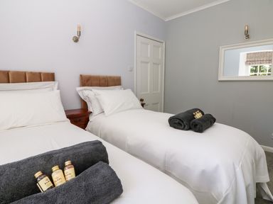 A bedroom with two single beds with white bedding and gray towels on the beds at Culdrose Manor in Helston